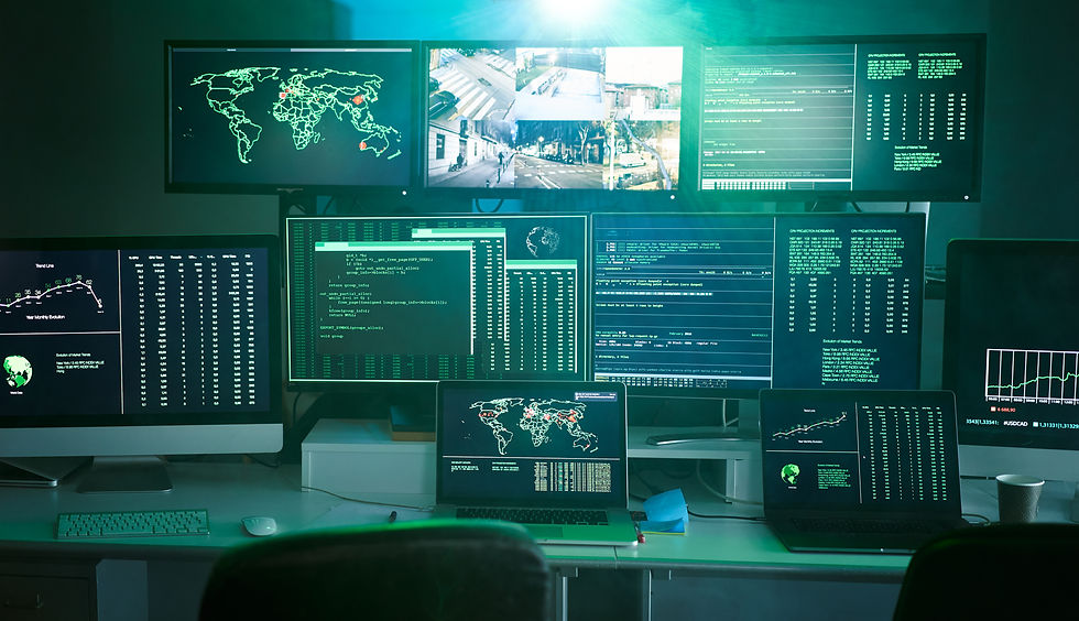 Biurko z wieloma monitorami pokazującymi mapy świata, wykresy i kod w zielono-niebieskim świetle, jak centrum monitoringu.